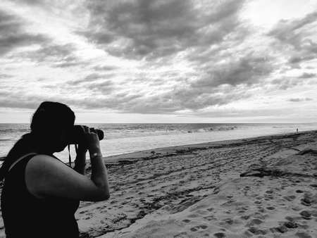 woman with a camera on a beach at sunset