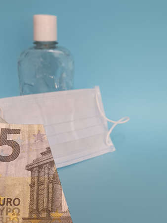 european banknote of five euro, mask, bottle with gel alcohol and blue backgroundの写真素材