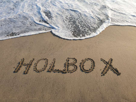 Holbox text handwritten in beach sand, background and texture