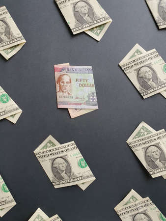 american one dollar bills and jamaican banknote of fifty dollars on the black background