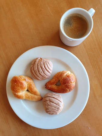 cup of coffee, plate with pieces of sweet bread on the wooden tableの写真素材