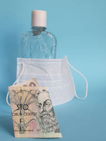 czech banknote of 100 korun, face mask, bottle with gel alcohol and blue backgroundの写真素材