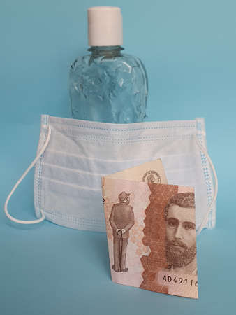 Colombian banknote of 5000 pesos, face mask, bottle with gel alcohol and blue backgroundの写真素材