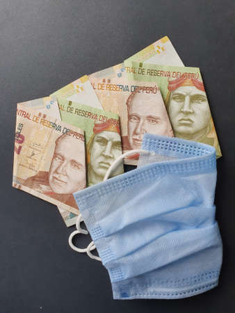 blue disposable mask and peruvian banknotes of different denominations