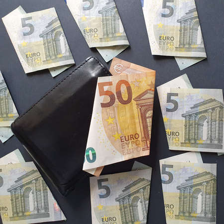 european banknote of fifty euro, black leather wallet and five euro bills