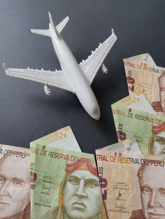 figure of a white plastic plane and peruvian banknotes of different denominations