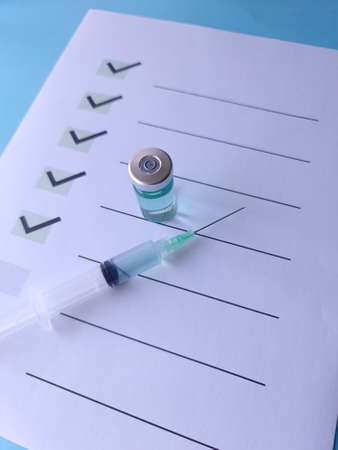 medicine bottle and syringe on a sheet with list of goalsの写真素材