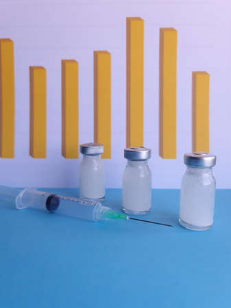 medicine bottles, syringe on the blue table and background with bars graph