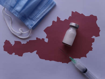 medicine bottle, mask and syringe on a sheet of paper with a map of Austriaの写真素材