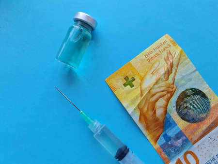 swiss banknote of ten francs, medicine bottle and syringe on the blue backgroundの写真素材