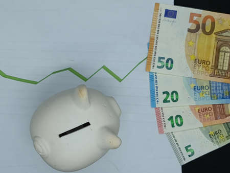 european banknotes and piggy bank on background with rising trend green line, view from aboveの写真素材