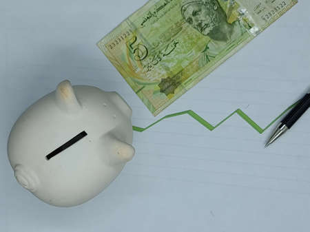 tunisian banknote and piggy bank on background with rising trend green line, view from above