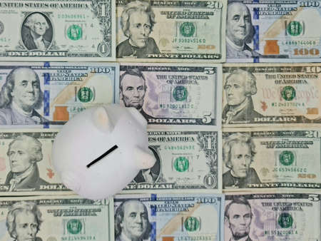 white piggy bank and background with american dollar bills, view from above