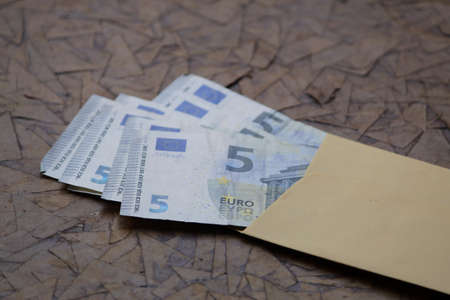 european banknotes in yellow paper envelope on brown surfaceの写真素材