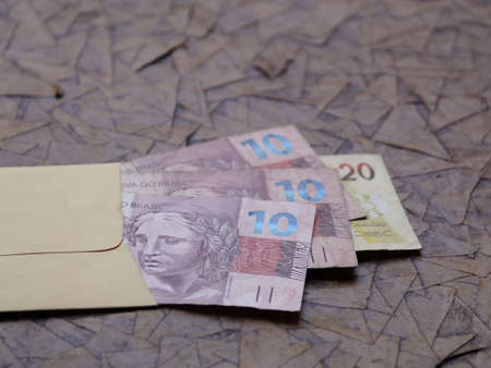 brazilian banknotes in yellow paper envelope on brown surfaceの写真素材