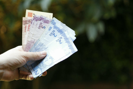 hand of a woman holding brazilian banknotes in a gardenの写真素材