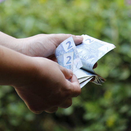 hands of a woman counting brazilian banknotes in a gardenの写真素材