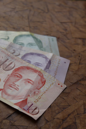 stacked singaporean banknote of different denominations on the brown surfaceの写真素材