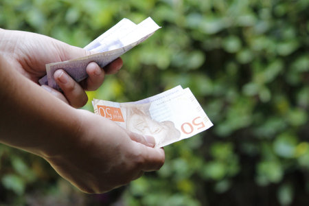 hands of a woman holding swedish banknotes in a garden