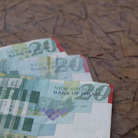 stacked israeli banknotes of twenty shekels on the brown surfaceの写真素材