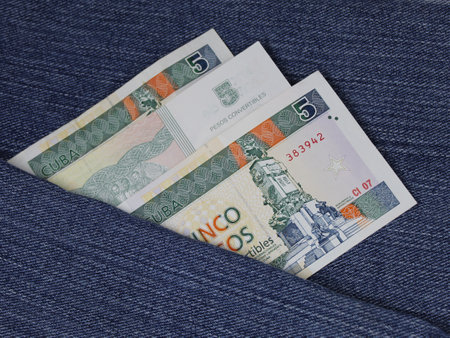 Cuban banknotes of five pesos between blue denim fabricの写真素材