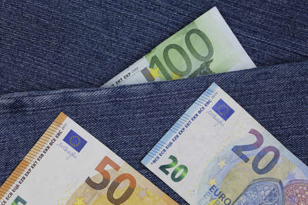 european banknotes of different denomination between blue denim fabricの写真素材