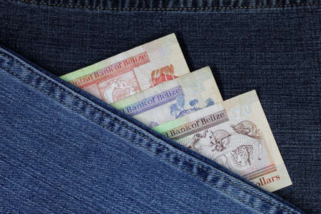 belizean banknotes of different denomination between blue denim fabricの写真素材