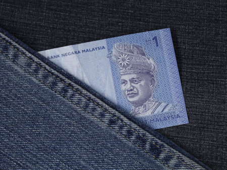 malaysian banknote of one ringgit between blue denim fabric