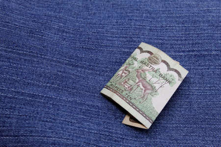 nepalese banknote of ten rupees between blue denim fabricの写真素材