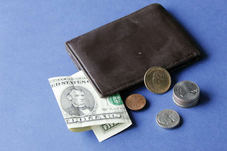 american five dollars bill, coins and brown leather wallet on the blue background