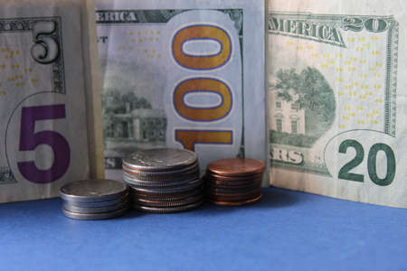 approach to stacked coins and american dollar banknotes of different denomination