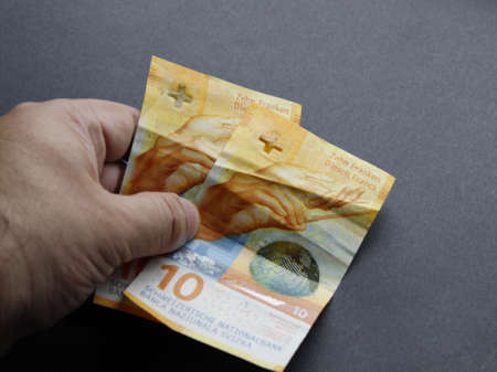 hand of a man holding swiss banknotes of ten francsの写真素材
