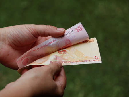 hand of a woman holding turkish banknotes in a park