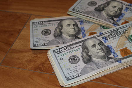 stacked american dollars banknotes on the wooden surface