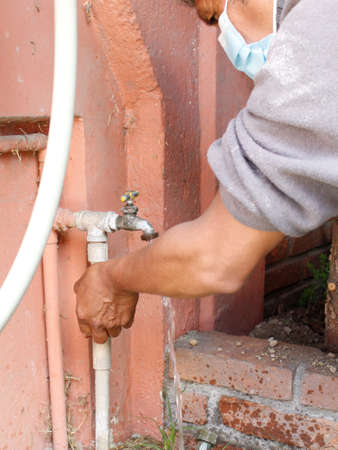 hand of a man checking a water tap in a gardenの写真素材