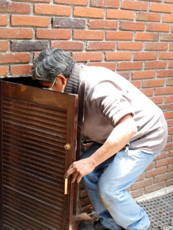 adult man opening the door of a small cellarの写真素材