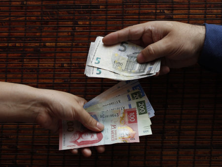 hands of two people exchanging european banknotes and mexican billsの写真素材