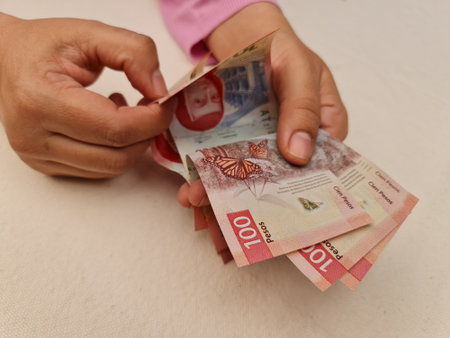 approach to hands of a woman holding and counting mexican banknotes