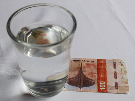 norwegian banknote and glass cup with drinkable water