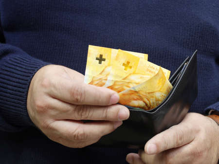 hands of a man keeping swiss banknotes in a walletの写真素材