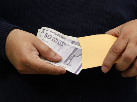 hands of a man keeping danish banknotes in a paper envelopeの写真素材