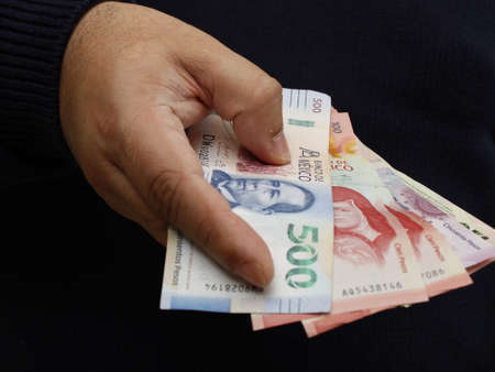 hand of a man holding mexican banknotes of different denominationの写真素材