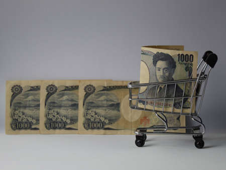 japanese banknotes of 1000 yen and shopping cart on white backgroundの写真素材