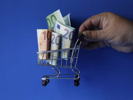 hand of a man holding a shopping cart with european billsの写真素材