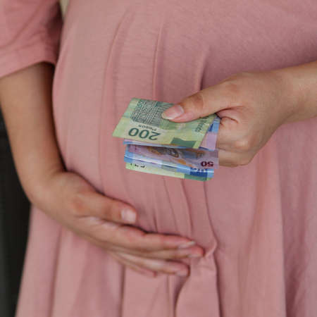 hand of a pregnant woman holding mexican moneyの写真素材