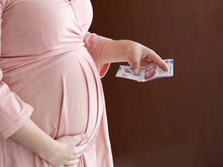 hand of a pregnant woman holding mexican moneyの写真素材