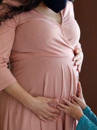 hands of a minor touching the belly of a pregnant woman