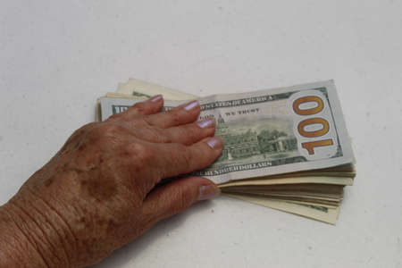 hands of an older woman on the american dollars banknotesの写真素材