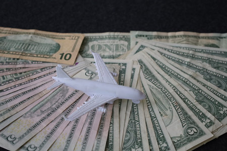 figure of a white plane and stacked american dollars billsの写真素材