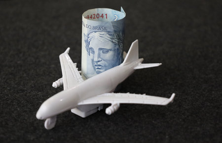 rolled up brazilian banknote of two reais and figure of a white plane
